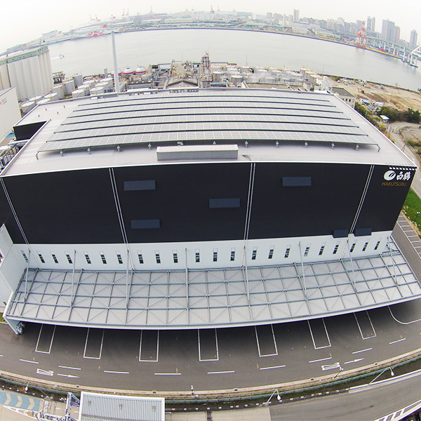 2012年に竣工した灘魚崎工場（ボトリング工場）です。1～3階は物流倉庫、4～6階が生産ラインとなっています。灘魚崎工場の屋上にも太陽光パネルを設置し、CO2排出量の削減を図っています。